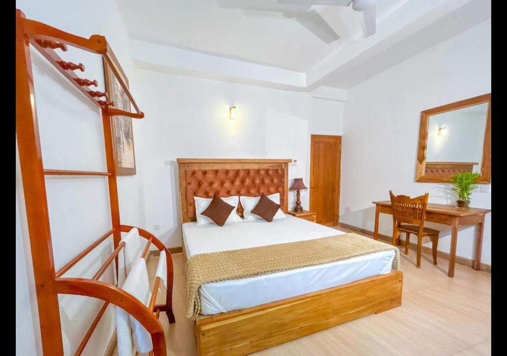 a bedroom with a bed and a table and a desk at New Arverne Villa Kandy in Kandy