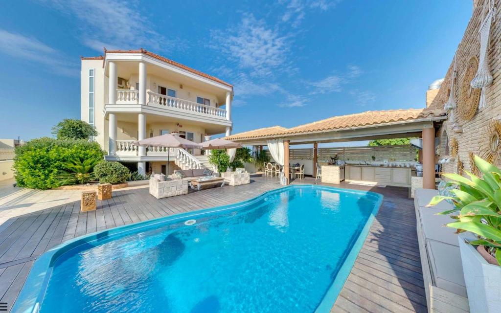a swimming pool in front of a house at Marilyn Manor, Exclusive Hideway, By ThinkVilla in Gouves