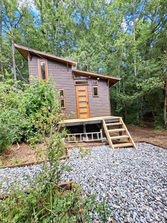 a tiny house in the woods with a porch at Refugio Purrunko in Pucón