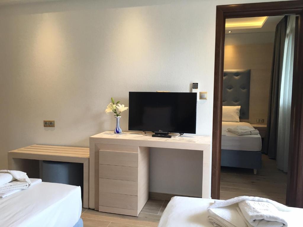 a room with a desk with a television and a mirror at Vergos Hotel in Vourvourou