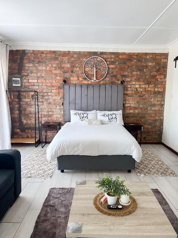 a bedroom with a large bed and a brick wall at Cozy Cottage in Langebaan