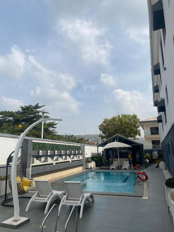 a swimming pool with chairs next to a building at 2020 Apartment Katampe in Mama
