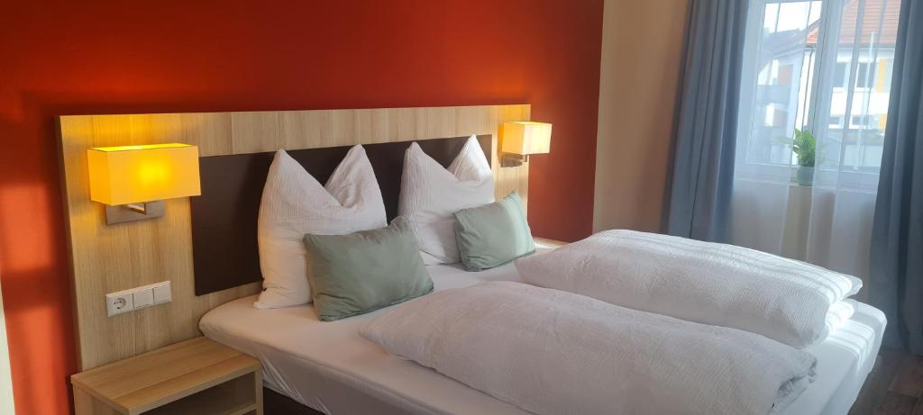 ein Schlafzimmer mit einem Bett mit weißen Laken und Kissen in der Unterkunft Hotel Pflug in Dornhan