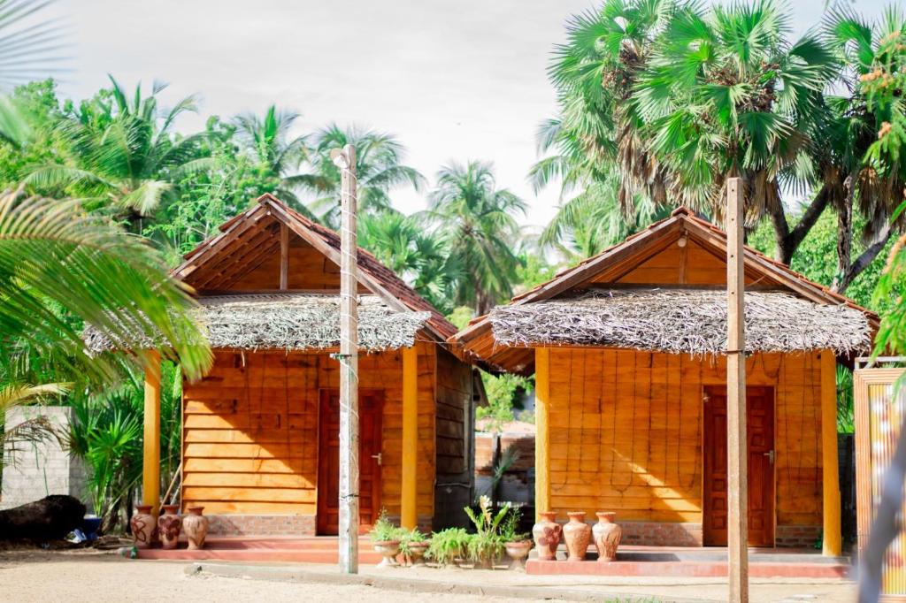 two small wooden houses with palm trees in the background at Beach View Resort in Batticaloa