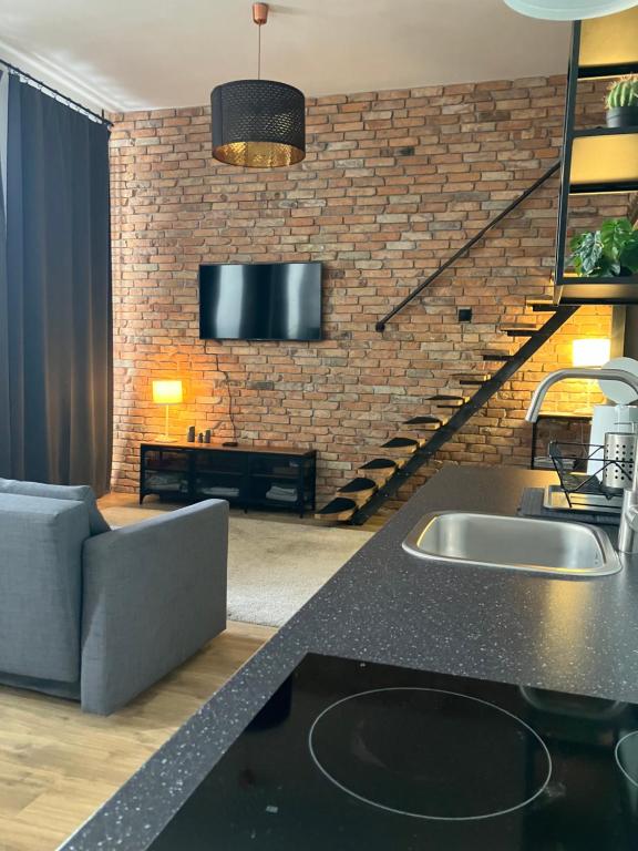 a kitchen with a sink and a living room at Apartament Kołobrzeska in Piła