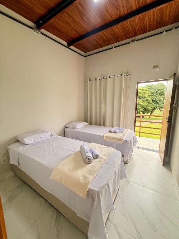 two beds in a room with a window at Hotel e Pousada Martini in Sorriso