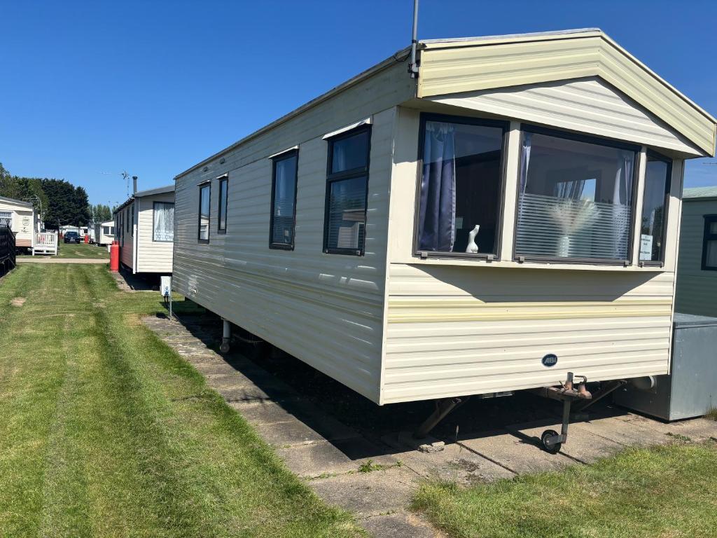 a green and white trailer with a dog in the window at 6 berth static in Skegness in Chapel Saint Leonards