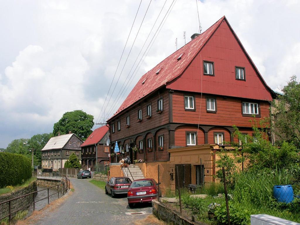 a large wooden house with a red roof on a street at Apartmány u Náměstí in Chřibská