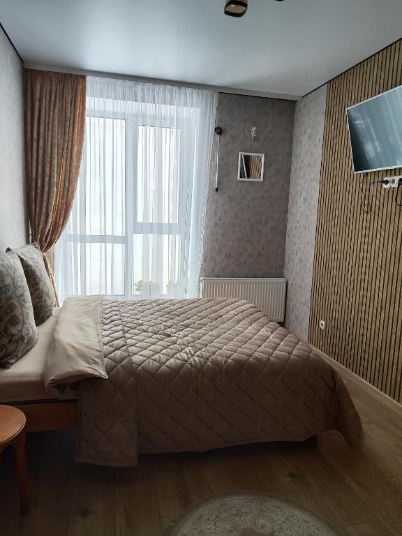 a bedroom with a bed and a large window at Апартаменты у самому Центрі в новому будинку біля ПЛАЗИ - ОЩАДБАНК in Khmelnytskyi