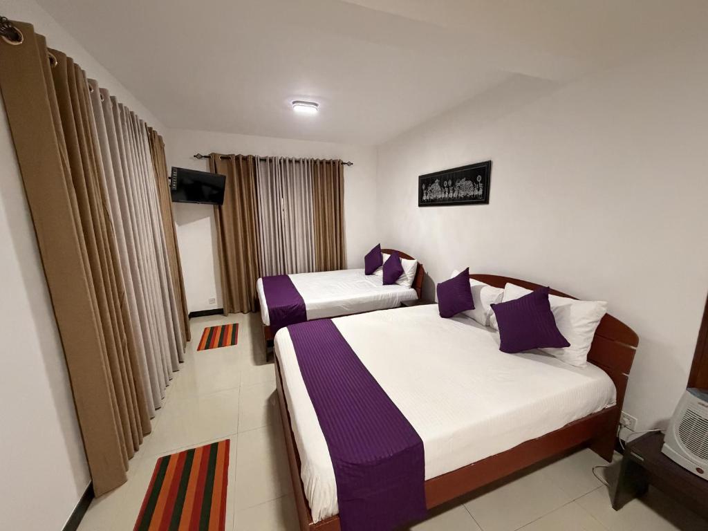 two beds in a hotel room with purple pillows at Sylvan Crest Ella in Ella