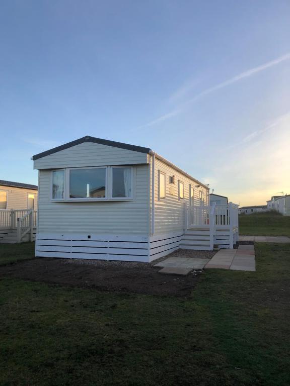 a small white house sitting on top of a field at Dunes Escape in Lossiemouth