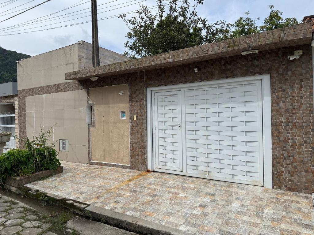 a white garage door on a brick building at Casa em Mongaguá in Mongaguá