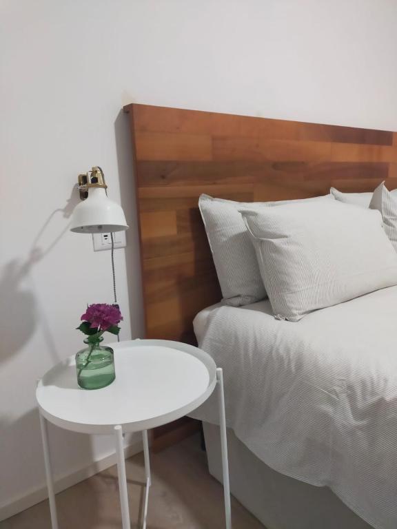 a white table with a vase of flowers on a bed at Ca' Rino - alloggio turistico in Vedelago