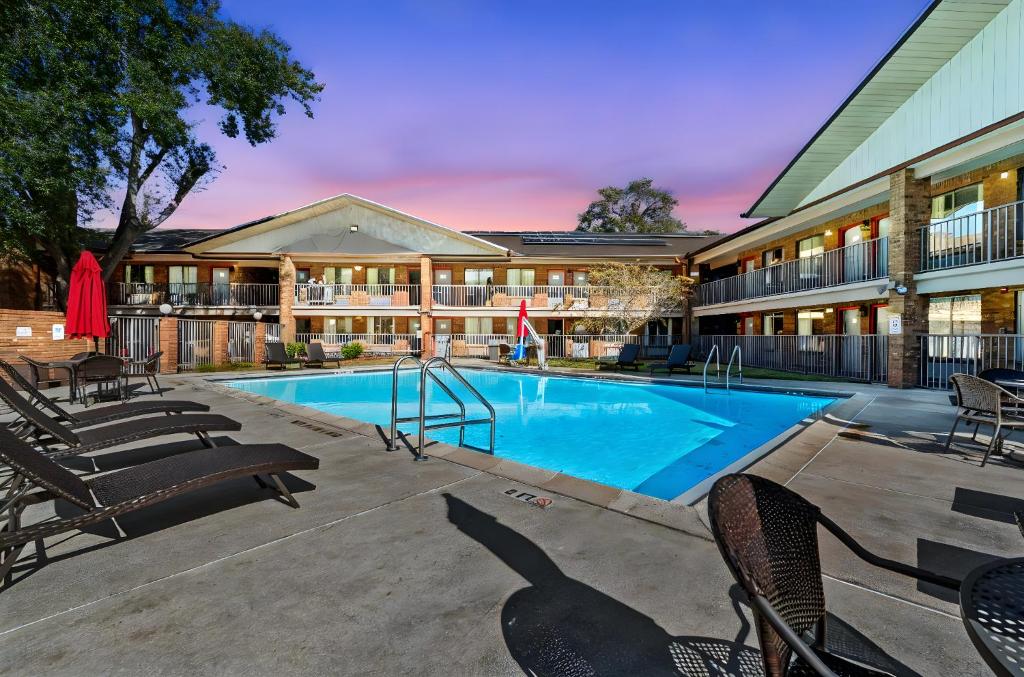 a swimming pool with chairs and a building at Ramada by Wyndham Temple Terrace/Tampa North in Tampa
