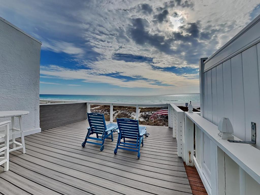 two blue chairs sitting on a deck looking at the ocean at Tiki Tango Hideaway in Panama City Beach