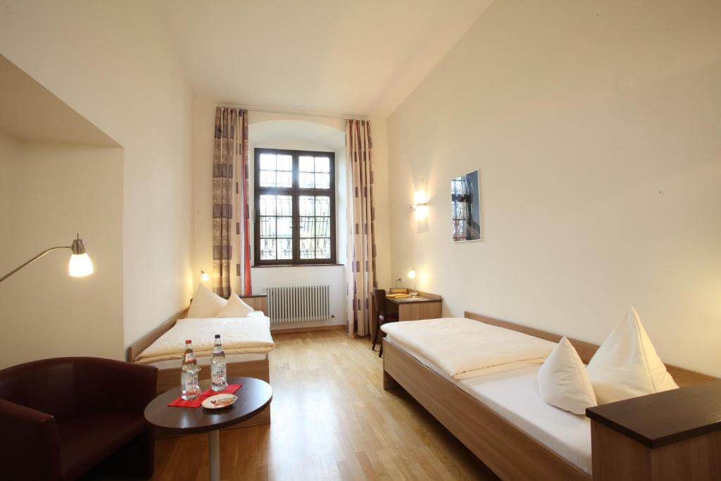 Habitación pequeña con cama, sofá y mesa. en Kloster Obermarchtal en Obermarchtal