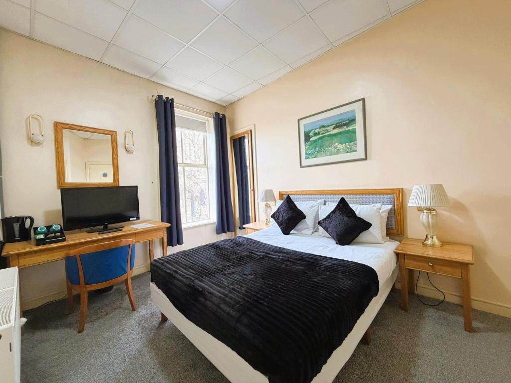 a bedroom with a bed and a desk and a television at Throstles Nest Hotel in Liverpool