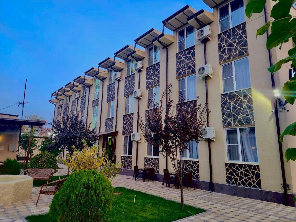 a building with a courtyard with chairs and trees at Tashkent apart hotel in Tashkent