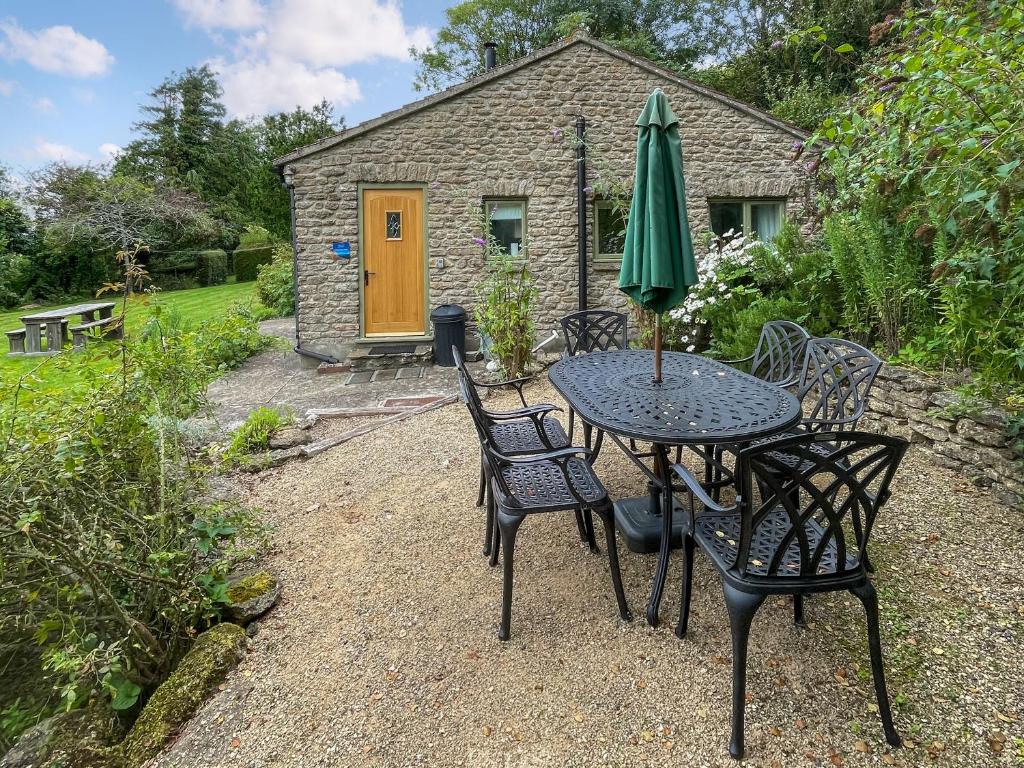 a table and chairs with a green umbrella on a patio at Whispering Pines - Uk51248 in Swyre