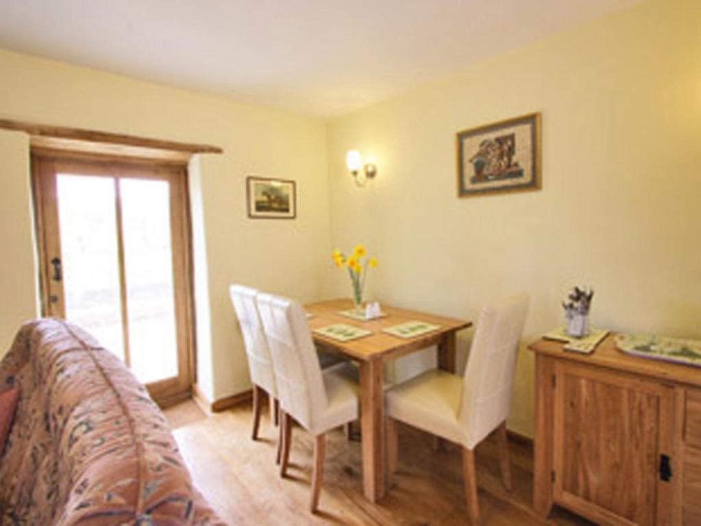a dining room with a wooden table and white chairs at The Brewhouse in Foxham