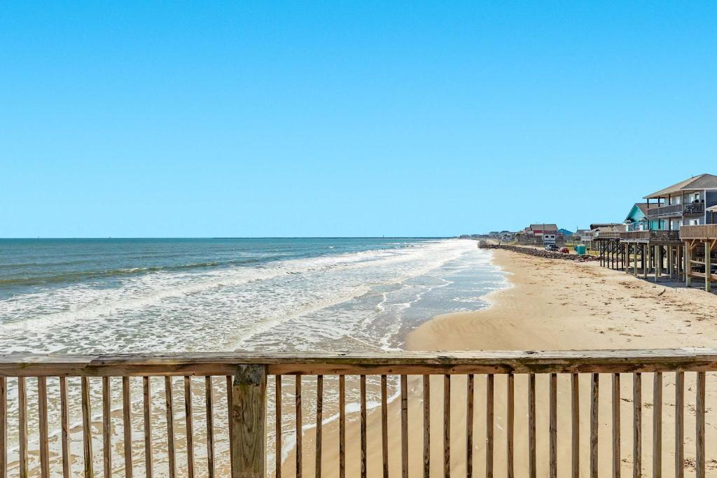 a beach with a wooden fence and the ocean at Iconic A Frame Sleep Over the Gulf in Surfside Beach