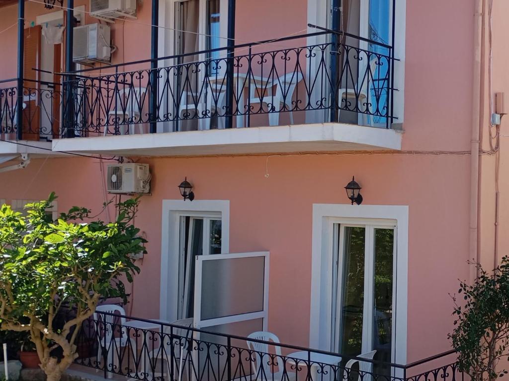 a pink building with a balcony and a tv on it at Apartments Elena in Kavos