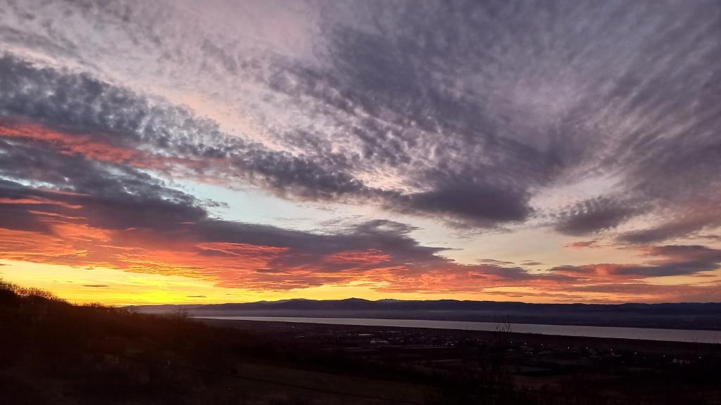 a sunset with a cloudy sky over a body of water at Casa Wylak Winery in Uileacu de Criş