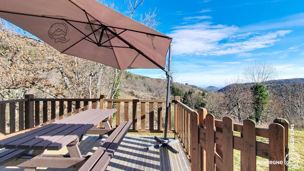 a picnic table with an umbrella on a wooden deck at Chalet de la Gougère 1 in Chambon-sur-Lac