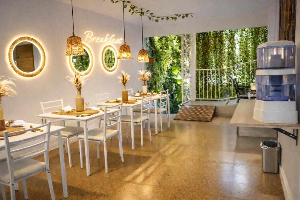 a dining room with white tables and white chairs at Muguet House Granada in Cali
