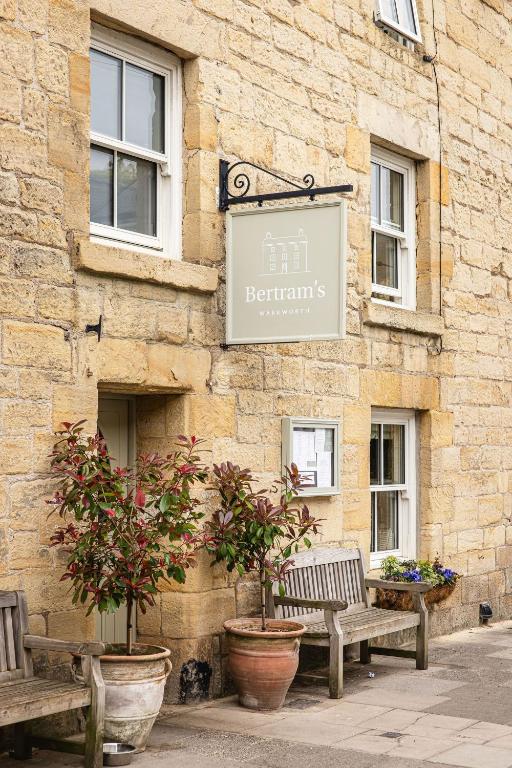 two benches in front of a building with a sign at Bertram's in Warkworth