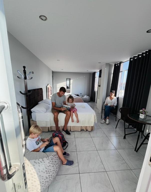 a family sitting on a bed in a hotel room at Sun Terrace Ilo Loft in Ilo