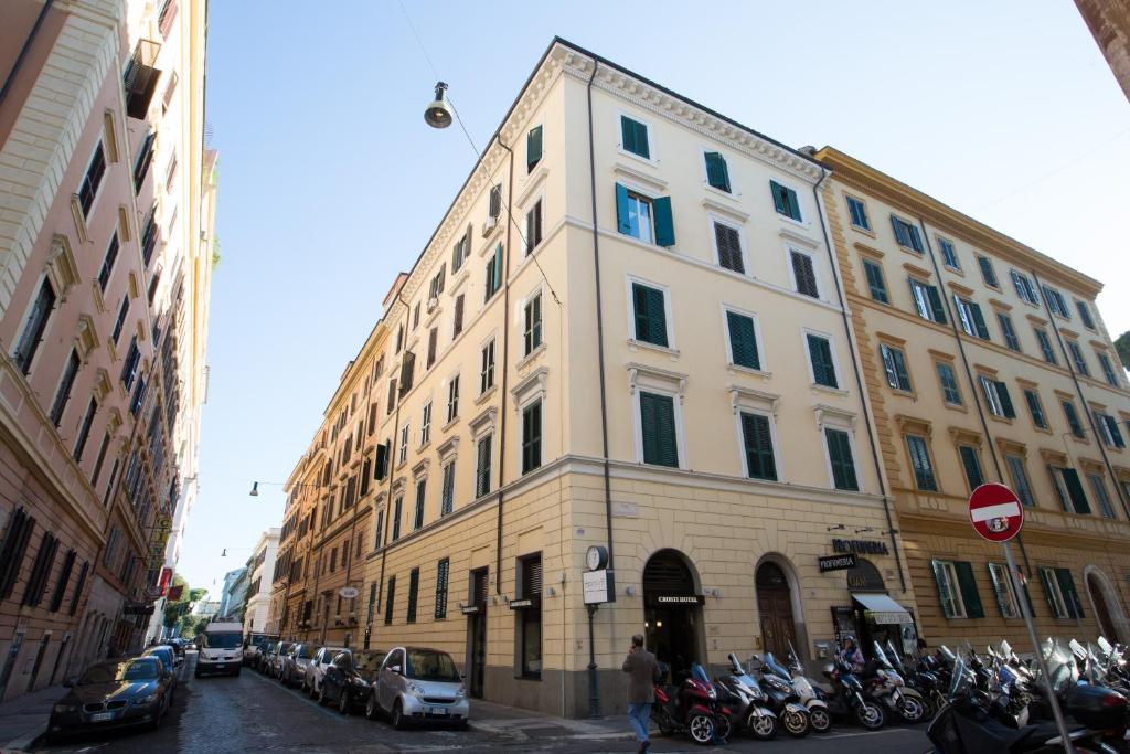 um edifício alto e branco com motos estacionadas em frente em Crosti Hotel em Roma