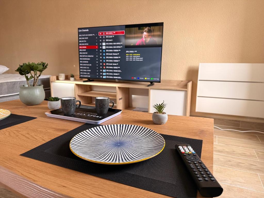 a table with a plate and a remote control at Appartement jacuzzi et spa étoile Mystérieuse in Belfort