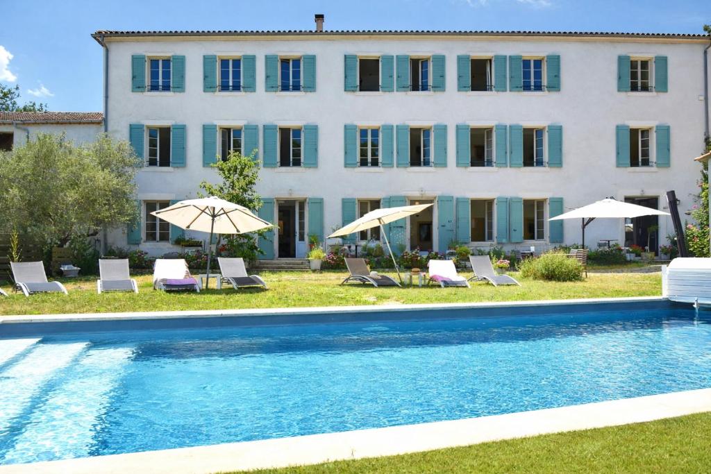 a pool with chairs and umbrellas in front of a building at Domaine de la Salutière - Charme & Confort au cœur du Pays Cathare in Lauraguel