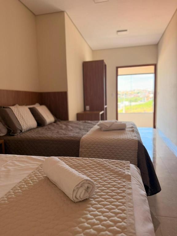 a hotel room with two beds and a window at Fonsecas House Suíte Privativas in Paraguaçu