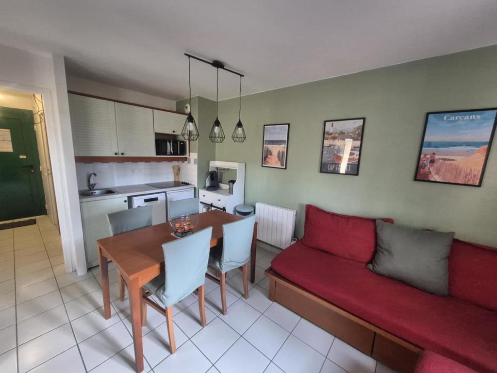 a living room with a red couch and a table at Appartement Carcans Maubuisson in Carcans