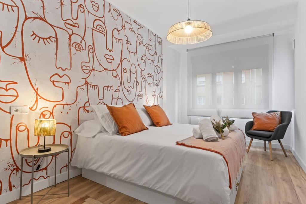 a bedroom with a large white bed with orange pillows at Picasso, para 6 personas, espacioso piso de diseño in Gijón