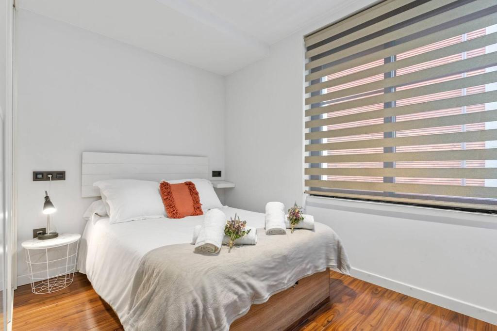 a white bedroom with a large window and a bed at Plaza del Carmen in Gijón