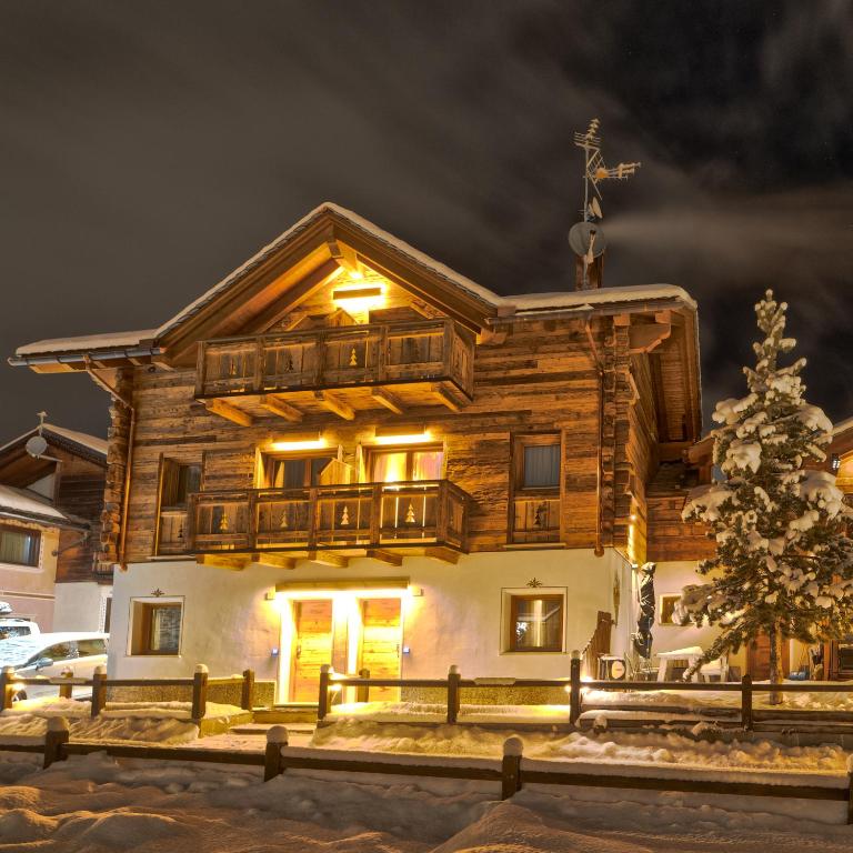 a log house with a christmas tree in front of it at Livigno Chalets in Livigno