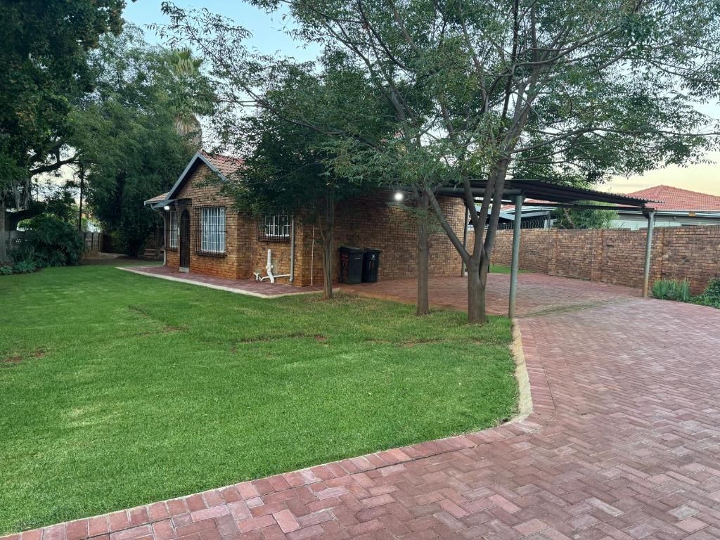a brick house with a tree in the yard at ORT Tranquil Stay in Boksburg