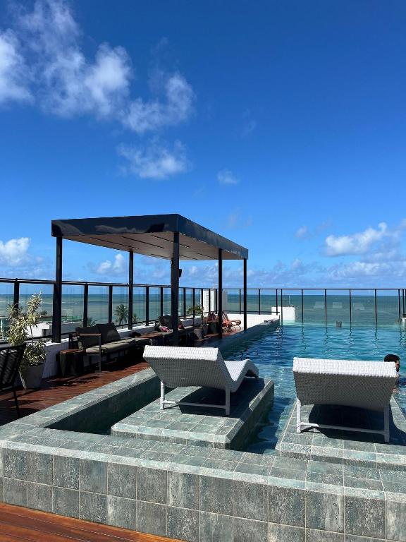 a swimming pool with two chairs and a pavilion at Get One - João Pessoa in João Pessoa