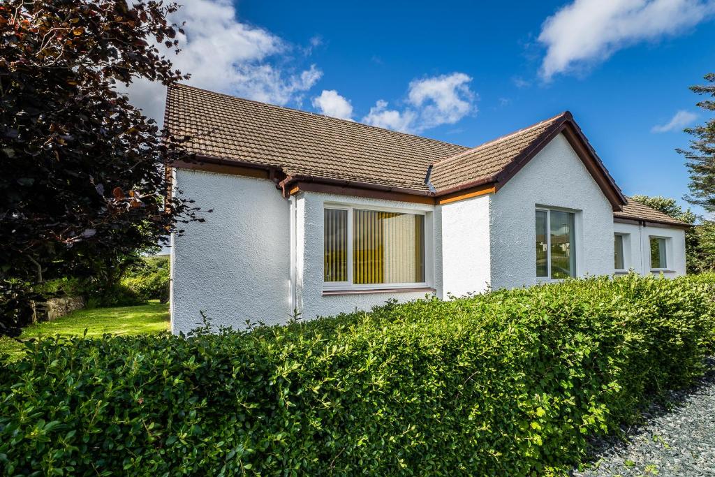 a white house with a hedge in front of it at Tigh Na Sith in Aultbea