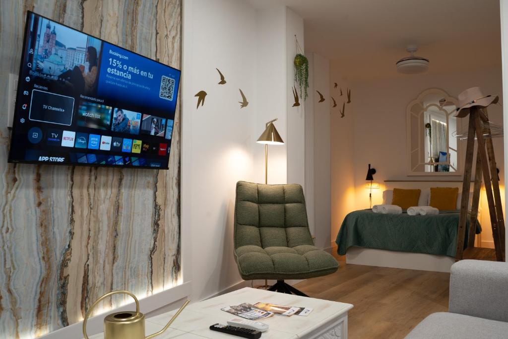 a living room with a chair and a tv on a wall at Judería Suite Jaén in Jaén