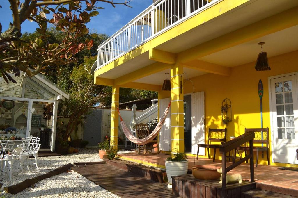 a yellow house with a hammock on a porch at Hospedaria Canto do Morro in Bombinhas