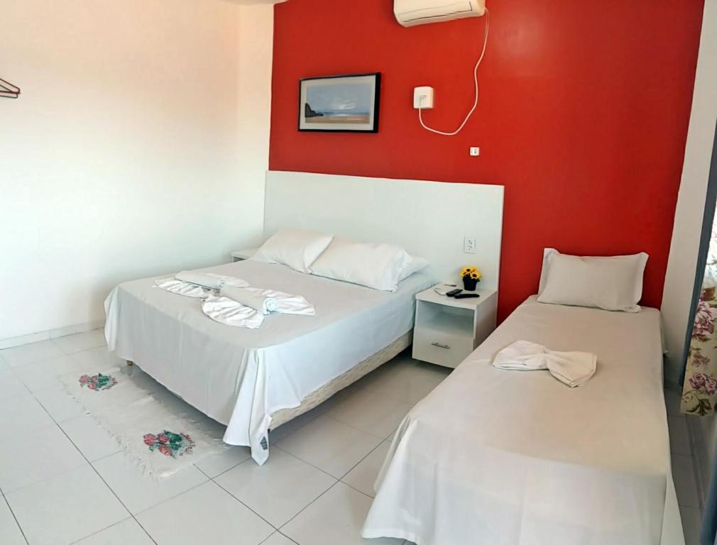 a bedroom with two beds and a red wall at Pousada Beira Rio Parnaíba in Parnaíba