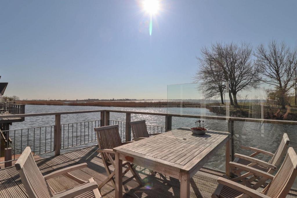 a wooden table and chairs on a deck next to the water at Villa Seaview met Sauna in Makkum