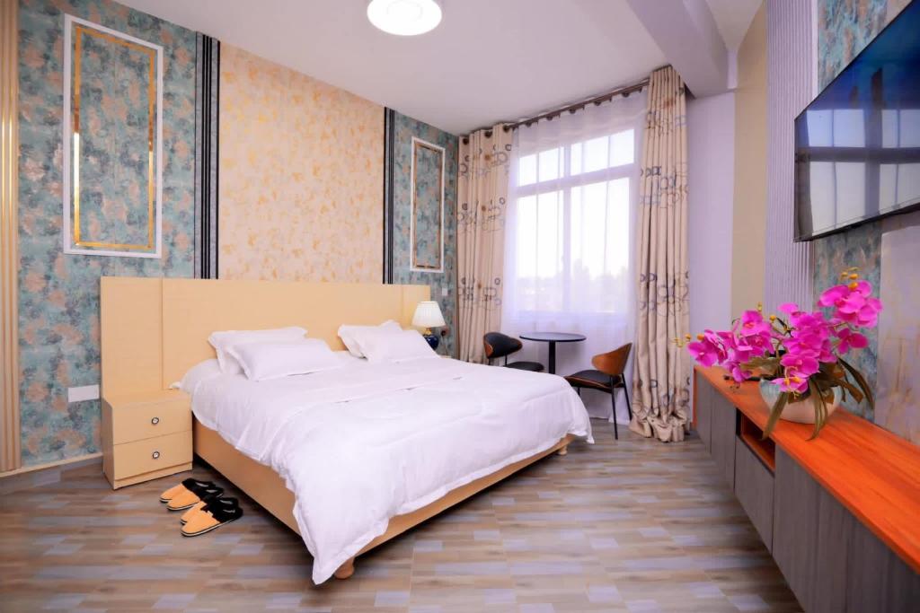 a bedroom with a large white bed and a window at Vegas Chillout Suites in Kampala