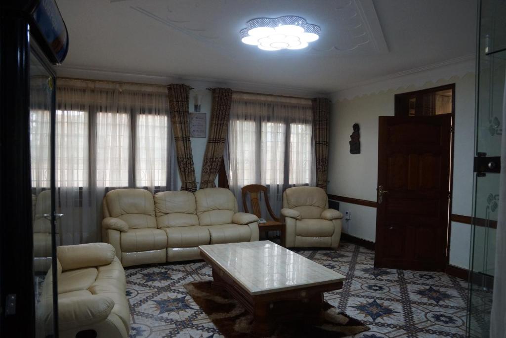 坎帕拉的住宿－Cosmil Executive Suites Najjanankumbi Kampala，客厅配有沙发、椅子和桌子