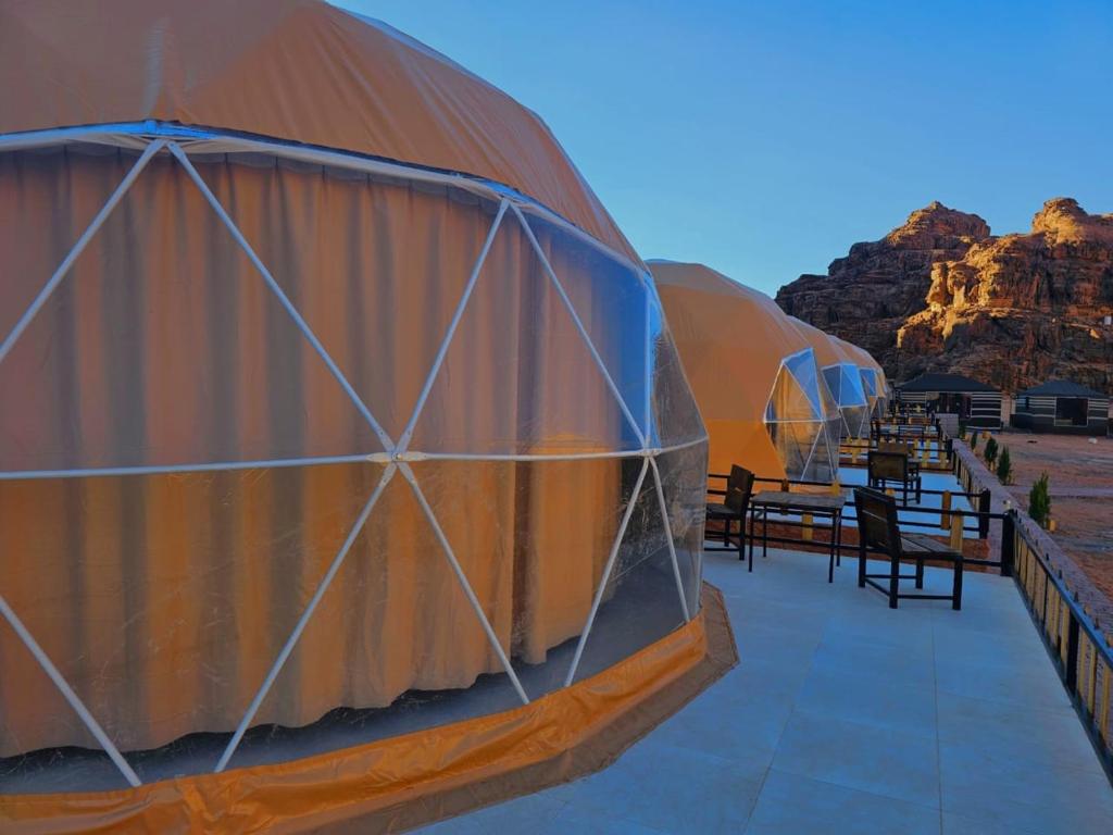 a row of tents in the desert with tables and benches at Wadi rum Rozana camp in Wadi Rum