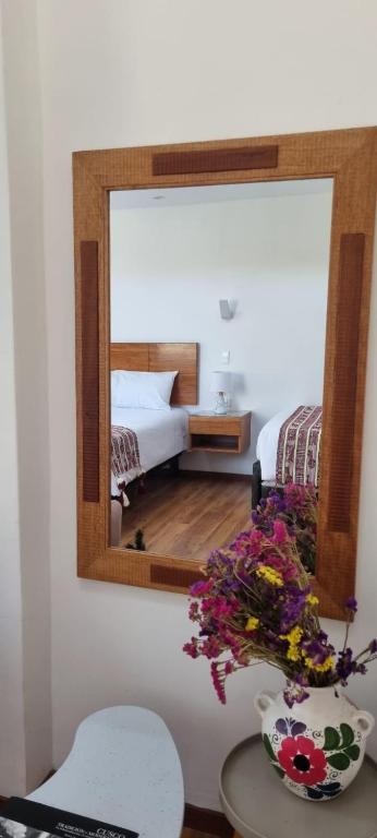 a bedroom with a mirror and a table with a vase of flowers at Florez de la Villa Apartments & Suites in Cusco